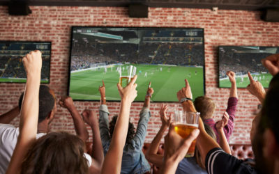 Rear View Of Friends Watching Game In Sports Bar On Screens Rear View Of Friends Watching Game In Sports Bar On Screens