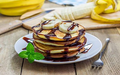 Stack of pancakes with banana and chocolate syrup