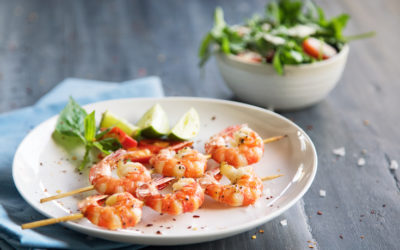 Grilled shrimps on skews with lime slices and salad