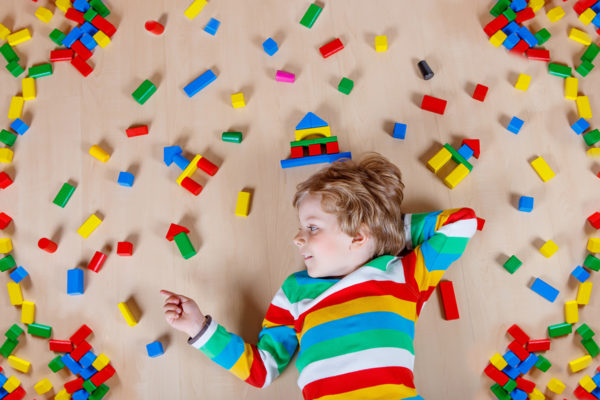 blonde child laying with colorful blocks