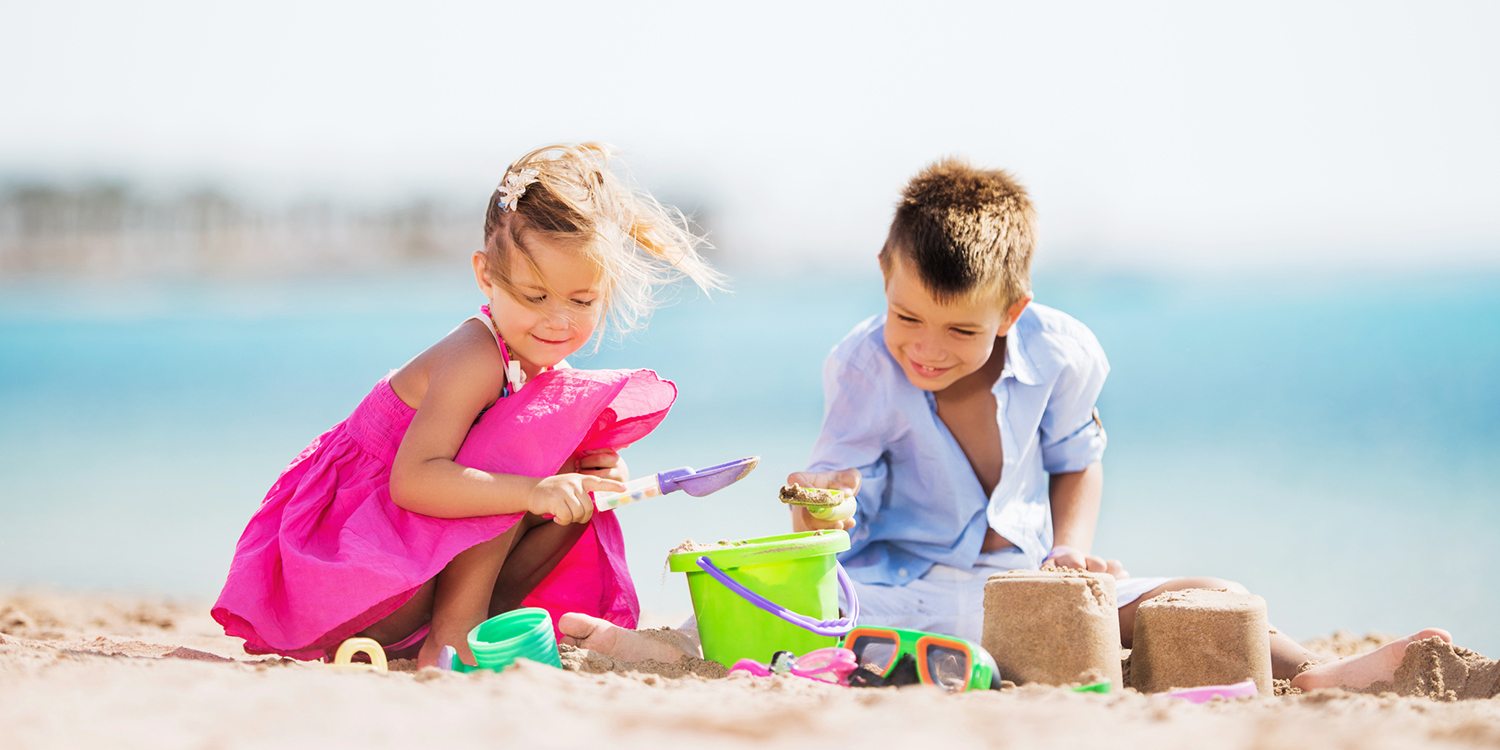 Little boy and girl playing with toys at the beach and enjoying in summer. Copy space.